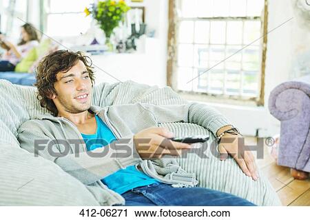Stock Image - Man watching television in beanbag chair. Fotosearch