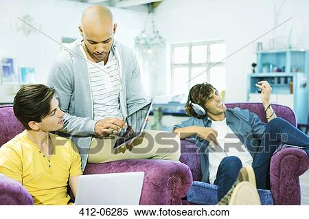 Stock Photography - Men relaxing together in living room. Fotosearch