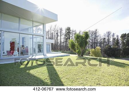 Stock Photo - Modern house casting shadows on manicured lawn. Fotosearch