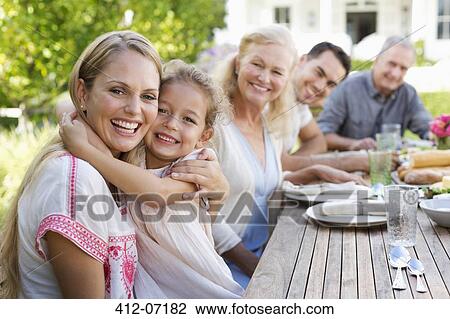 Mother and daughter hugging at table outdoors View Large Photo Image Stock Image - Mother and daughter hugging at table outdoors. Fotosearch