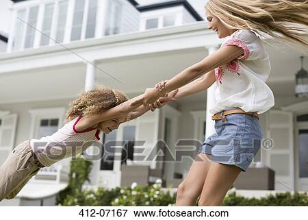 Stock Photo - Mother and daughter playing outside house. Fotosearch