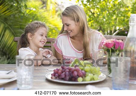 Mother and daughter smiling at table outdoors View Large Photo Image Stock Image - Mother and daughter smiling at table outdoors. Fotosearch