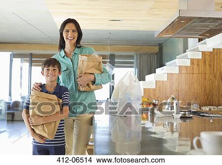 Picture - Mother and son holding groceries in kitchen. Fotosearch