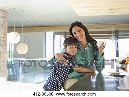 Stock Image - Mother and son smiling in kitchen. Fotosearch