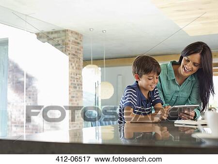 Stock Photo - Mother and son using tablet computer in kitchen. Fotosearch