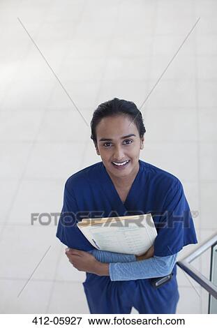 Nurse holding folders in hospital hallway View Large Photo Image Stock Photo - Nurse holding folders in hospital hallway. Fotosearch