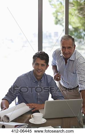 Older man and younger man working together at desk View Large Photo Image Stock Photography - Older man and younger man working together at desk. Fotosearch