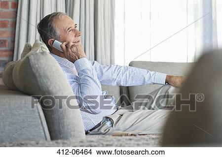 Older man talking on cell phone on sofa View Large Photo Image Picture - Older man talking on cell phone on sofa. Fotosearch