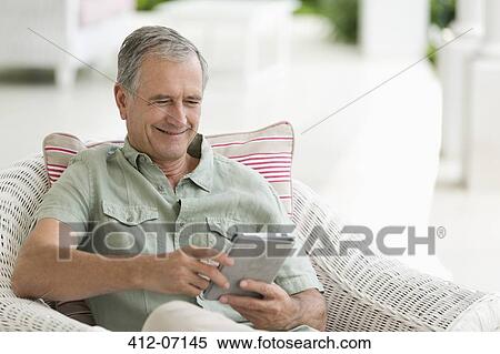 Stock Photography - Older man using tablet computer on porch. Fotosearch