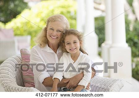 Stock Photo - Older woman and granddaughter smiling on porch. Fotosearch
