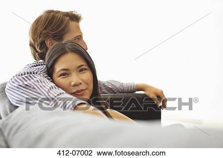 Smiling couple relaxing on sofa View Large Photo Image Stock Image - Smiling couple relaxing on sofa. Fotosearch