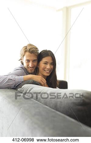 Smiling couple relaxing on sofa View Large Photo Image Stock Photo - Smiling couple relaxing on sofa. Fotosearch
