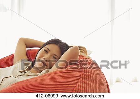 Smiling woman relaxing in beanbag chair View Large Photo Image Stock Photo - Smiling woman relaxing in beanbag chair. Fotosearch