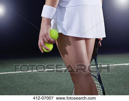 Stock Photo - Tennis player holding balls on court. Fotosearch