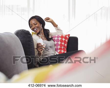 Woman listening to headphones on sofa View Large Photo Image Picture - Woman listening to headphones on sofa. Fotosearch