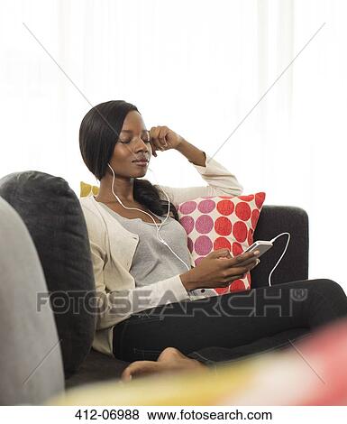 Woman listening to headphones on sofa View Large Photo Image Stock Photo - Woman listening to headphones on sofa. Fotosearch