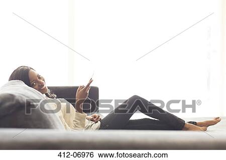 Woman listening to headphones on sofa View Large Photo Image Stock Photograph - Woman listening to headphones on sofa. Fotosearch