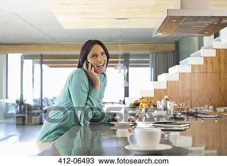 Woman talking on cell phone in kitchen View Large Photo Image Stock Image - Woman talking on cell phone in kitchen. Fotosearch