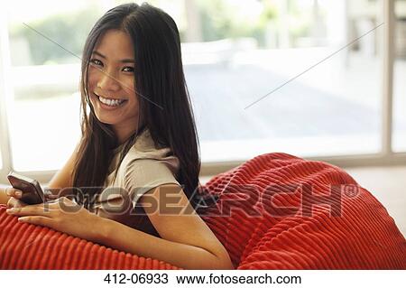 Woman using cell phone in beanbag chair View Large Photo Image Stock Image - Woman using cell phone in beanbag chair. Fotosearch