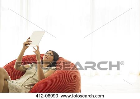 Woman using tablet computer in beanbag chair View Large Photo Image Stock Image - Woman using tablet computer in beanbag chair. Fotosearch