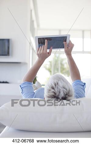 Woman using tablet computer on sofa View Large Photo Image Stock Photo - Woman using tablet computer on sofa. Fotosearch