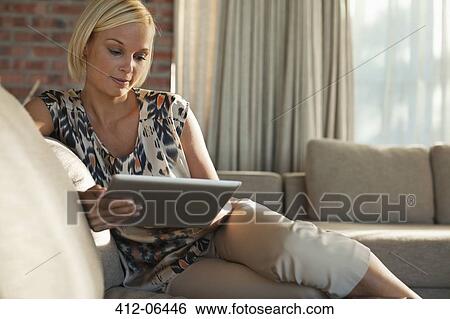 Woman using tablet computer on sofa View Large Photo Image Stock Photograph - Woman using tablet computer on sofa. Fotosearch