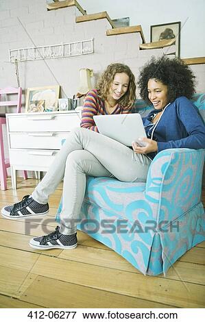 Women using laptop together in armchair View Large Photo Image Stock Photo - Women using laptop together in armchair. Fotosearch