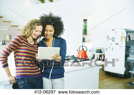 Stock Photo - Women using tablet computer in kitchen. Fotosearch