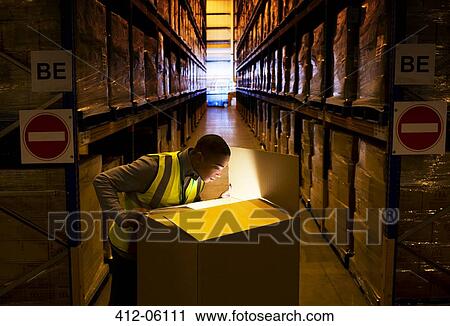 Worker opening glowing box in warehouse View Large Photo Image Stock Image - Worker opening glowing box in warehouse. Fotosearch