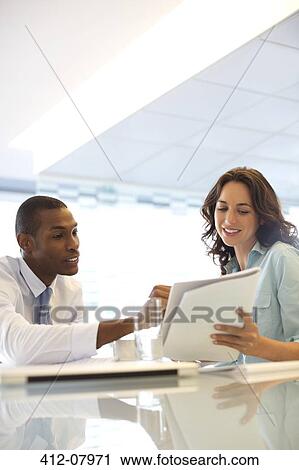 Stock Image - Businessman and businesswoman reviewing paperwork. Fotosearch