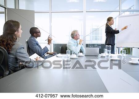 Businesswoman at flipchart leading meeting in conference room View Large Photo Image Stock Photo - Businesswoman at flipchart leading meeting in conference room. Fotosearch