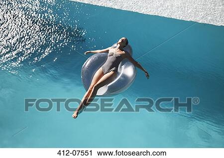 Stock Image - Carefree woman on ring in swimming pool. Fotosearch