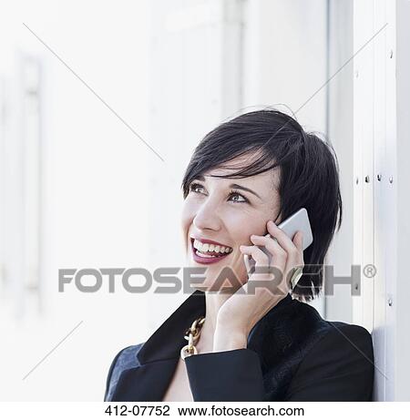Stock Image - Close up of smiling woman talking on cell phone. Fotosearch