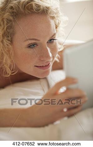 Close up of woman laying in bed using digital tablet View Large Photo Image Stock Image - Close up of woman laying in bed using digital tablet. Fotosearch