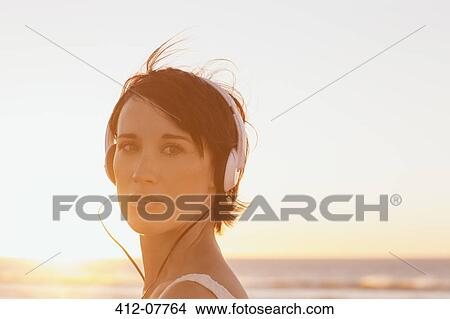 Close up portrait of confident woman wearing headphones at beach View Large Photo Image Picture - Close up portrait of confident woman wearing headphones at beach. Fotosearch