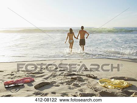 Couple holding hands and wading in ocean View Large Photo Image Stock Image - Couple holding hands and wading in ocean . Fotosearch