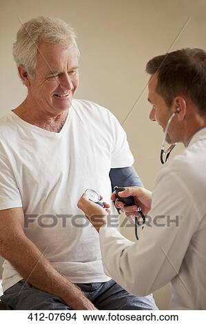 Picture - Doctor checking senior man's blood pressure in doctor's office. Fotosearch