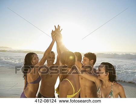 Friends high fiving in huddle at beach View Large Photo Image Picture - Friends high fiving in huddle at beach. Fotosearch
