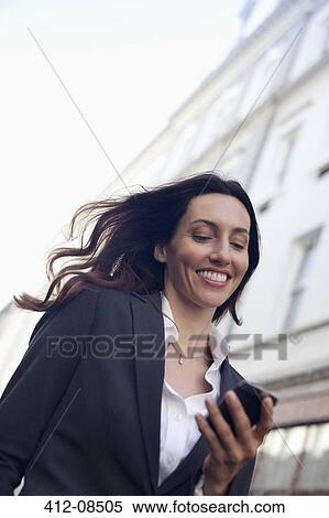 Stock Photography - Happy businesswoman text messaging with cell phone. Fotosearch