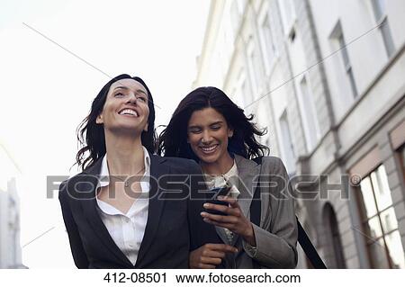Happy businesswomen text messaging with cell phone View Large Photo Image Stock Image - Happy businesswomen text messaging with cell phone. Fotosearch