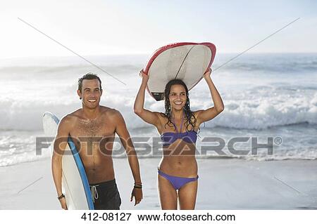 Happy couple carrying surfboards at beach View Large Photo Image Stock Photo - Happy couple carrying surfboards at beach. Fotosearch