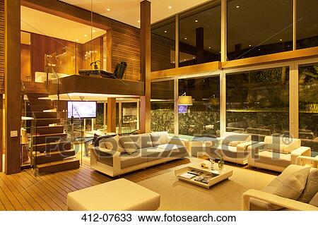 Illuminated modern living room at night View Large Photo Image Stock Image - Illuminated modern living room at night. Fotosearch
