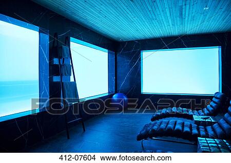 Lounge chairs in pool room facing windows with underwater view of swimming pool View Large Photo Image Picture - Lounge chairs in pool room facing windows with underwater view of swimming pool. Fotosearch