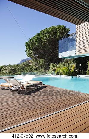 Stock Image - Luxury swimming pool and lounge chairs on deck. Fotosearch