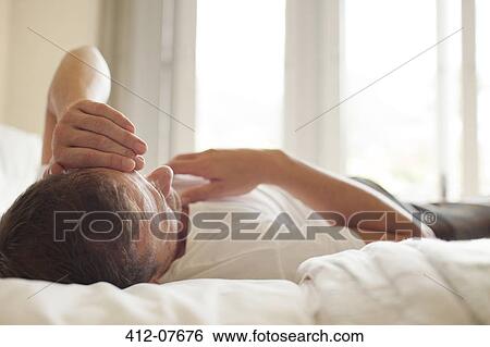 Man laying in bed with head in hands View Large Photo Image Stock Photograph - Man laying in bed with head in hands. Fotosearch