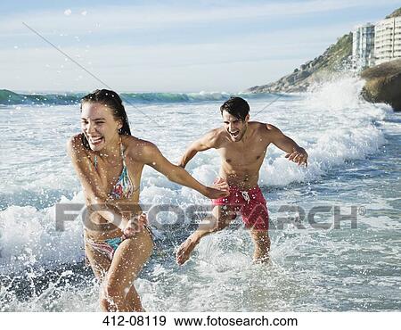 Playful couple splashing in ocean surf View Large Photo Image Stock Photo - Playful couple splashing in ocean surf. Fotosearch