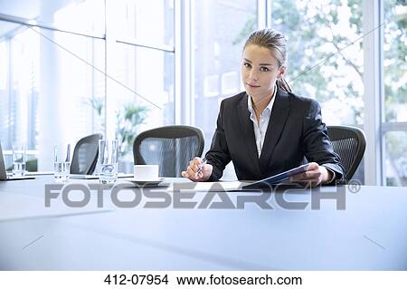 Portrait of serious businesswoman reviewing paperwork in conference room View Large Photo Image Picture - Portrait of serious businesswoman reviewing paperwork in conference room. Fotosearch