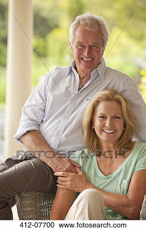 Stock Image - Portrait of smiling couple holding hands on patio. Fotosearch