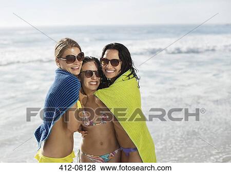 Portrait of smiling friends wrapped in towel at beach View Large Photo Image Stock Photo - Portrait of smiling friends wrapped in towel at beach. Fotosearch