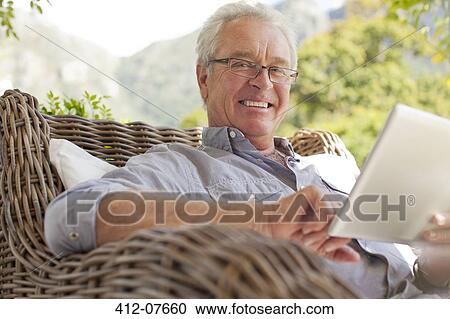Portrait of smiling man using digital tablet on patio View Large Photo Image Stock Image - Portrait of smiling man using digital tablet on patio. Fotosearch